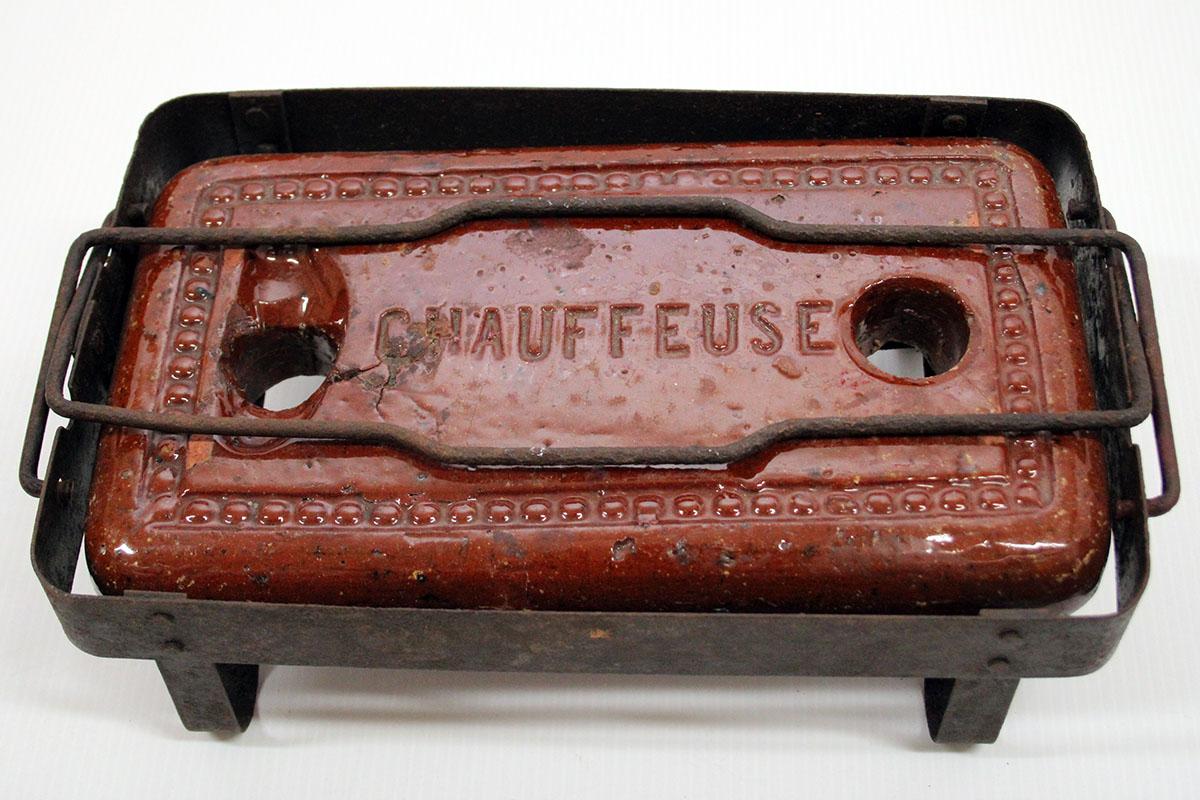 Chaufferette en terre cuite réfractaire vernissée, de forme rectangulaire, posée dans un piétement en métal