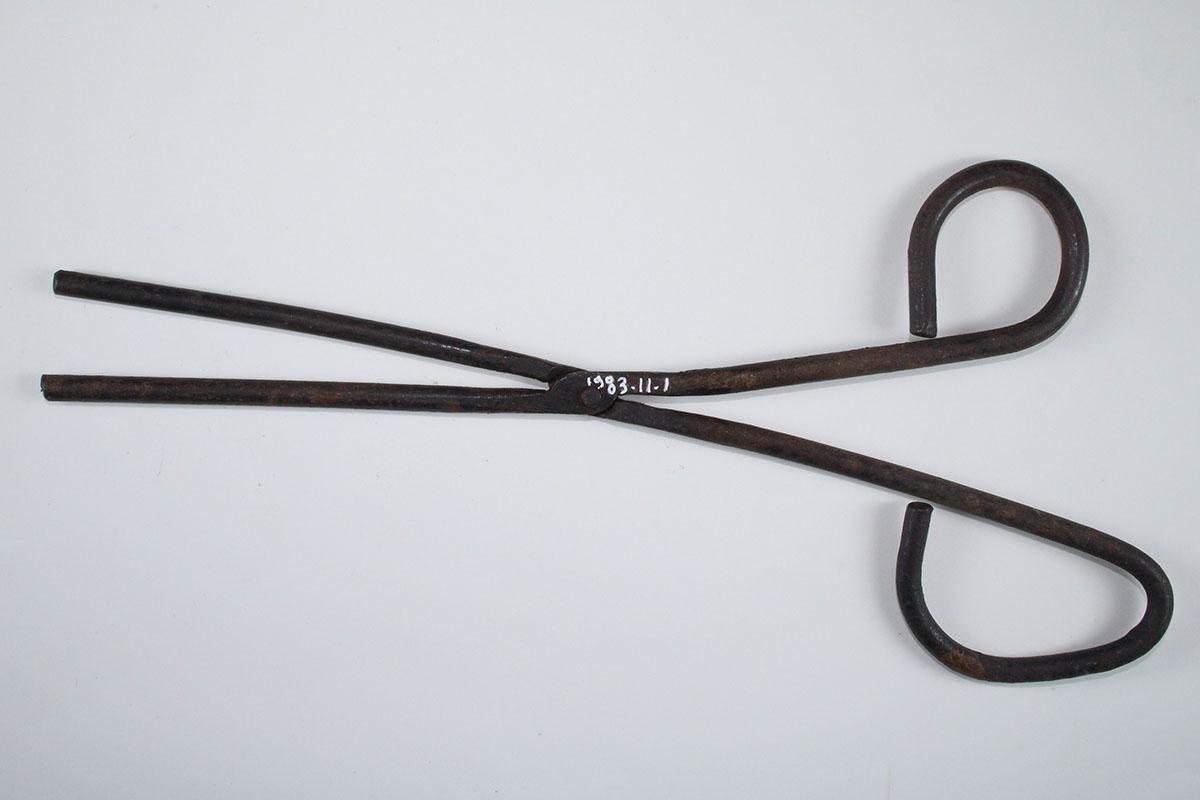 Fer à tuyauter de repasseuse ; instrument en métal, à longues branches articulées et fines, dont la forme rappelle une paire de ciseaux