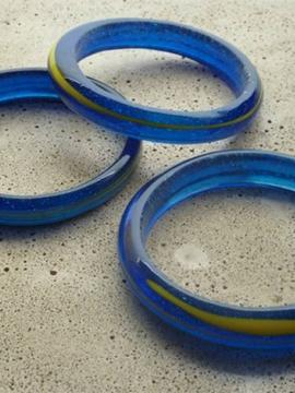 Trois bracelets en verre de couleur bleue et présentant un un insert circulaire de couleur jaune, fabriqués d'une seule pièce et sans fermoir