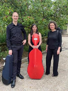 Trois membres du Quatuor Arezzo, photographiés dans la cour du musée. Chacun porte son instrument dans un étui.