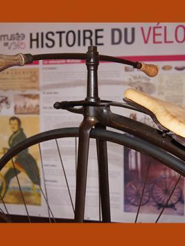 Photographie d'un vélo ancien, devant un panneau de présentation de l'histoire du vélo, au Musée du vélo de Moret-Loing-et-Orvanne