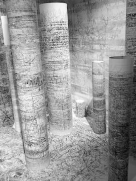 Oeuvre de Bertrand Flachot constituée de rouleaux de papier couverts de dessins et d'écriture, sur un fond en papier également recouvert d'inscriptions à l'encre noire.