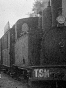 Au début du 20ème siècle, un train entre en gare. Au 1er plan sur le quai, une femme vue de dos, coiffée d'un chapeau