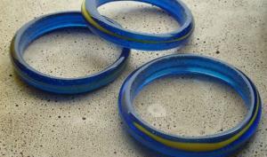 Trois bracelets en verre de couleur bleue et présentant un un insert circulaire de couleur jaune, fabriqués d'une seule pièce et sans fermoir