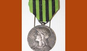 Médaille en métal, face représentant Marianne casquée, ruban en tissu rayé vert et noir