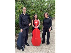 Trois membres du Quatuor Arezzo, photographiés dans la cour du musée. Chacun porte son instrument dans un étui.