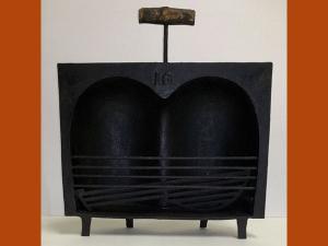 Coquille à rôtir en fonte avec une poignée en bois, surnommée "paire de fesses" en raison de sa forme.
