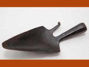 Outil en fer forgé, en forme de petite pelle pointue avec un crochet à droite. Le manche est manquant.