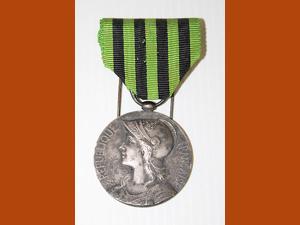 Médaille en métal, face représentant Marianne casquée, ruban en tissu rayé vert et noir