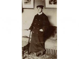 tirage photographique en noir et blanc représentant Pierre Mac Orlan, jeune, avec manteau long et casquette.