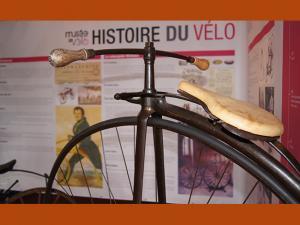 Photographie d'un vélo ancien, devant un panneau de présentation de l'histoire du vélo, au Musée du vélo de Moret-Loing-et-Orvanne