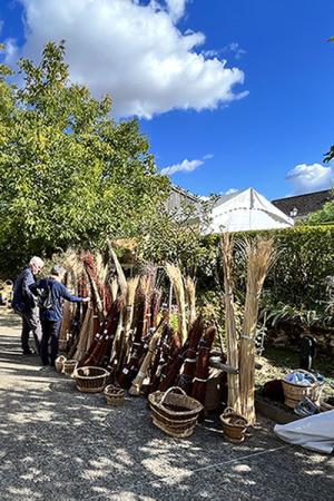 Photographie prise lors d'une précédente fête des vanniers : dans la cour du musée, des visiteurs sont arrêtés sur un stand de vente de vanneries et d'osier