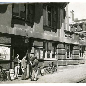 Vue de Londres, datée de 1934 : groupe d'hommes à l'entrée d'un bâtiment administratif. Photographie rapportée de Londres par Pierre Mac Orlan à l'occasion d'un de ses reportages.