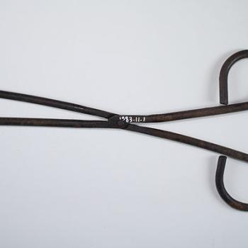 Fer à tuyauter de repasseuse ; instrument en métal, à longues branches articulées et fines, dont la forme rappelle une paire de ciseaux