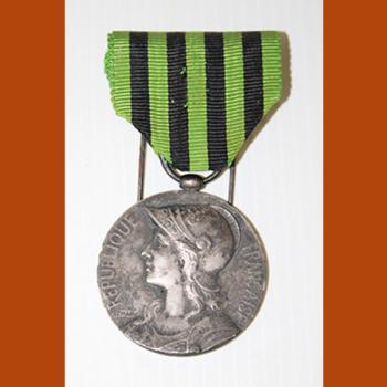 Médaille en métal, face représentant Marianne casquée, ruban en tissu rayé vert et noir