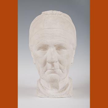 Sculpture en plâtre représentant la tête d'une vieille femme briarde ; ses traits sont marqués, ses cheveux plaqués en arrière par un bandeau.