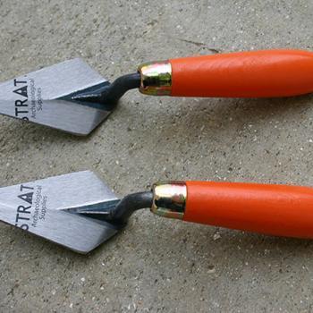 2 truelles d'archéologue ; le manche en bois est peint en orange, la truelle est de en forme de losange