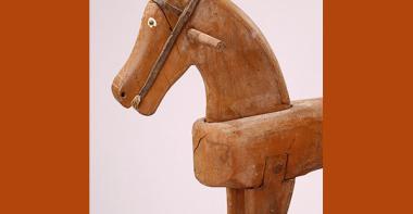 Avant-main d'un cheval à bascule en bois, des deux côtés de la tête se trouve une poignée. Les yeux sont en relief et leur tour est peint en blanc, le filet rudimentaire a été réalisé en cuir.