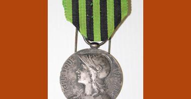 Médaille en métal, face représentant Marianne casquée, ruban en tissu rayé vert et noir