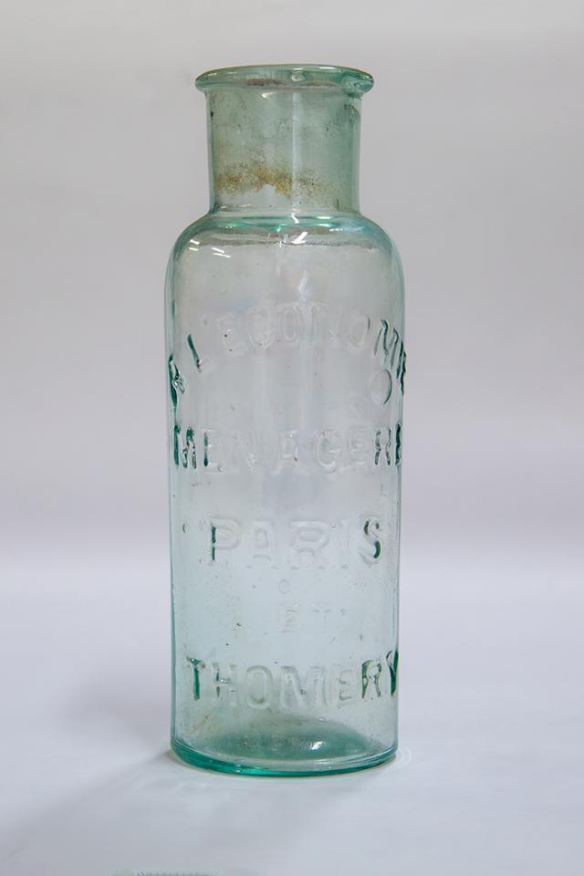 Flacon de conservation pour le raisin Chasselas, en verre transparent de couleur verte, avec des inscriptions en relief sur le corps du flacon, le goulot est large, pour permettre de recevoir une à deux grappes de raisin.