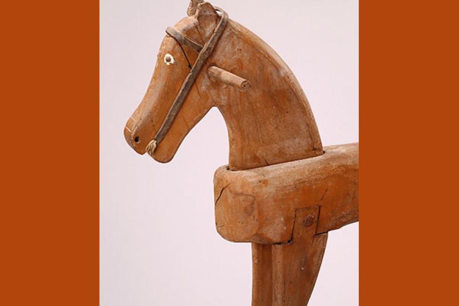Avant-main d'un cheval à bascule en bois, des deux côtés de la tête se trouve une poignée. Les yeux sont en relief et leur tour est peint en blanc, le filet rudimentaire a été réalisé en cuir.