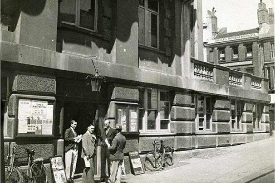 Vue de Londres, datée de 1934 : groupe d'hommes à l'entrée d'un bâtiment administratif. Photographie rapportée de Londres par Pierre Mac Orlan à l'occasion d'un de ses reportages.