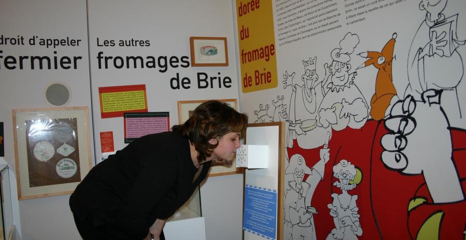 Une visiteuse découvre les arômes des boîtes à odeurs, lors d'une visite de l'exposition temporaire "Fromages de Brie"